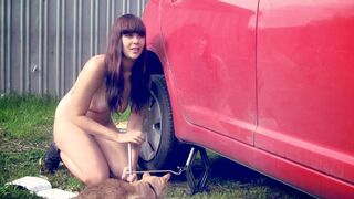 Naked girl at work. Changing a tire on the car shaking her big boobs