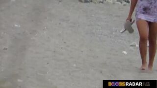 Nude lady is lying on the beach, while a horny voyeur is watching her shaved pussy